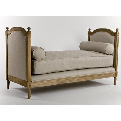 an old fashioned daybed with pillows on it's sides and back rests against a white wall