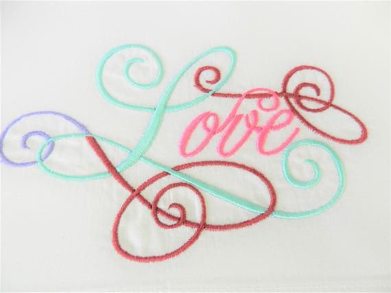 an embroidered piece with the word love on it and swirls in pink, blue, green, and purple