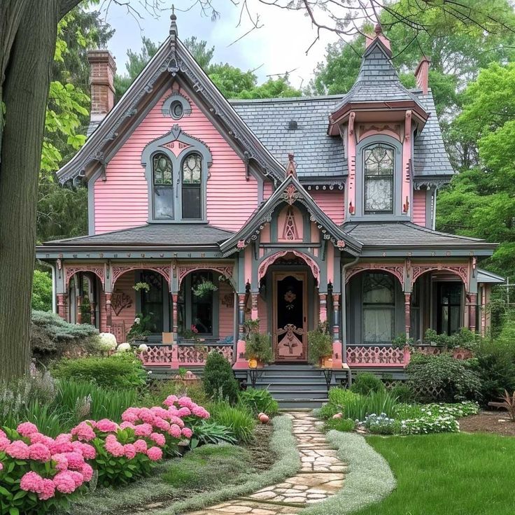 a pretty pink house with lots of flowers in the front yard