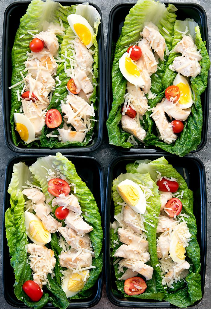 four plastic trays filled with lettuce topped with chicken, tomatoes and eggs