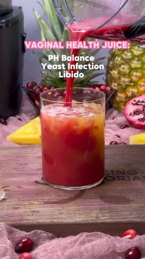 a drink being poured into a glass on top of a wooden table with fruit in the background