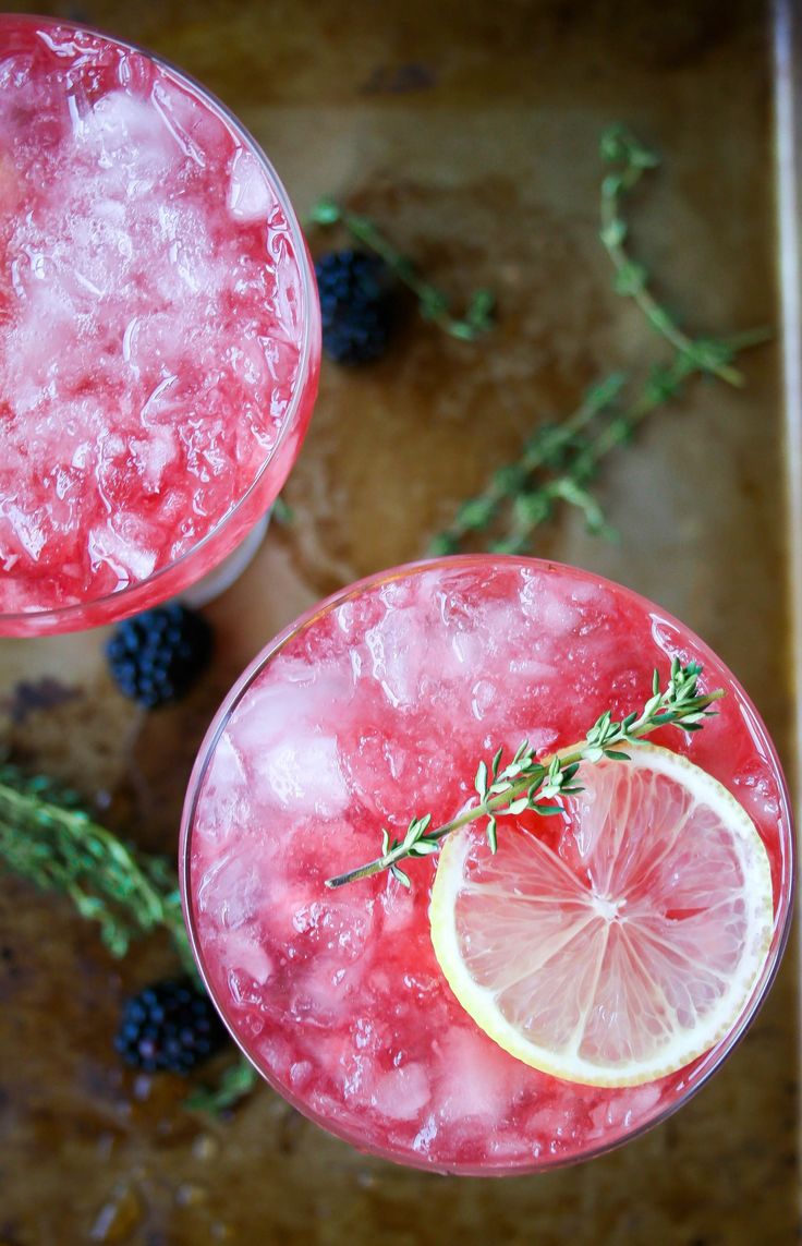 two glasses filled with pink lemonade and rosemary garnish