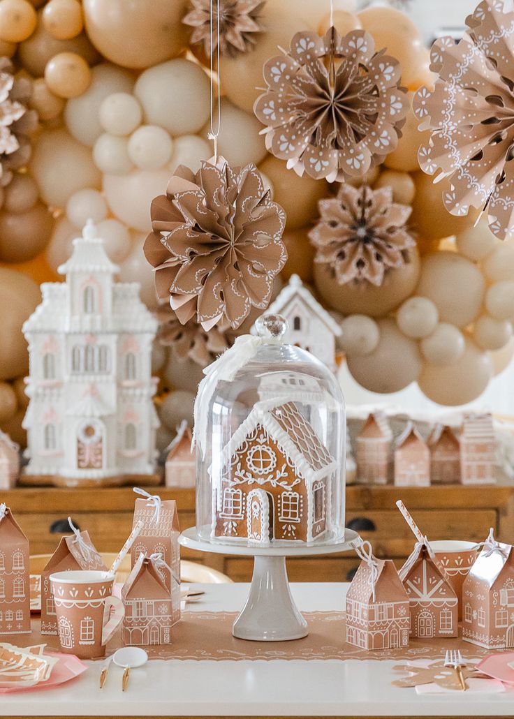 a table topped with gingerbread houses covered in frosting and paper snowflakes