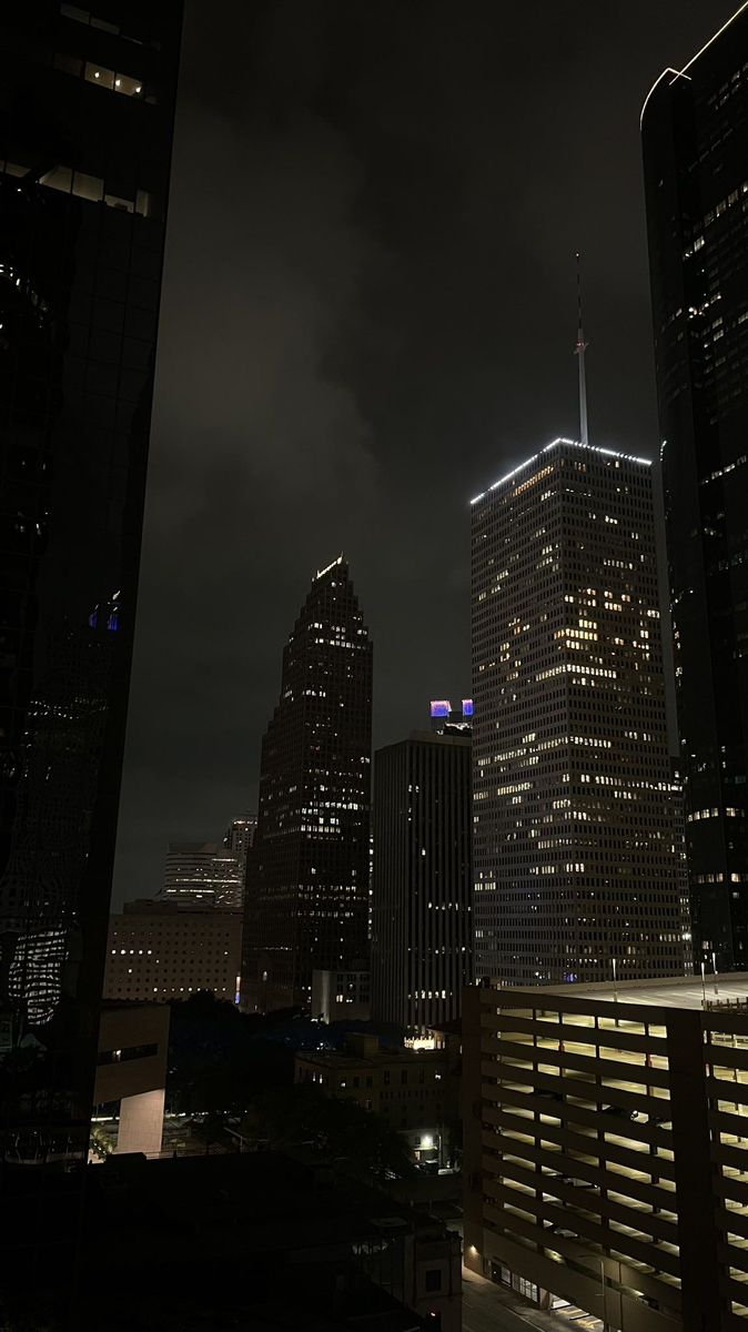 the city skyline is lit up at night, with skyscrapers in the foreground