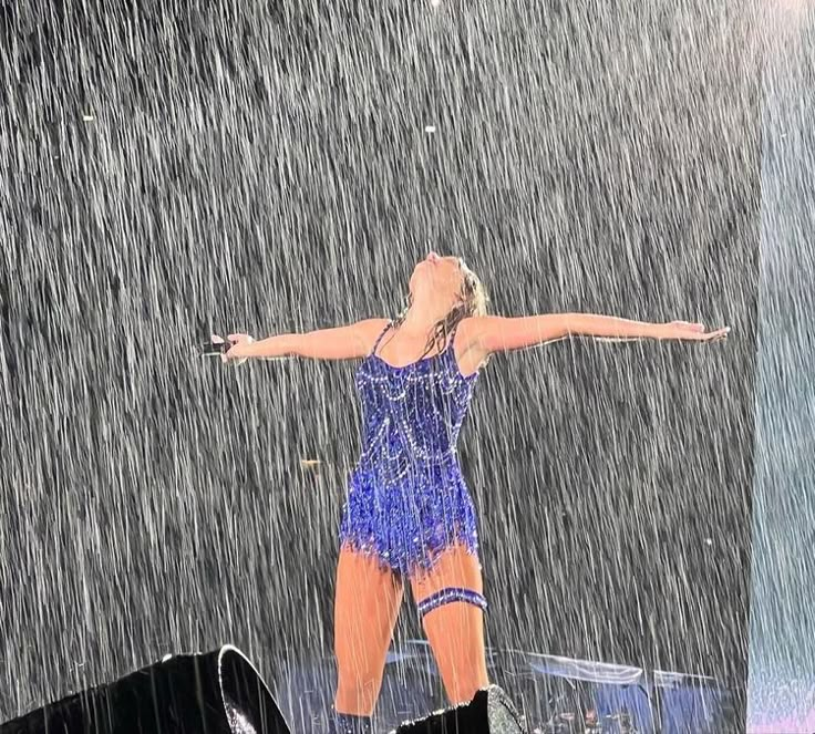 a woman standing in the rain with her arms outstretched