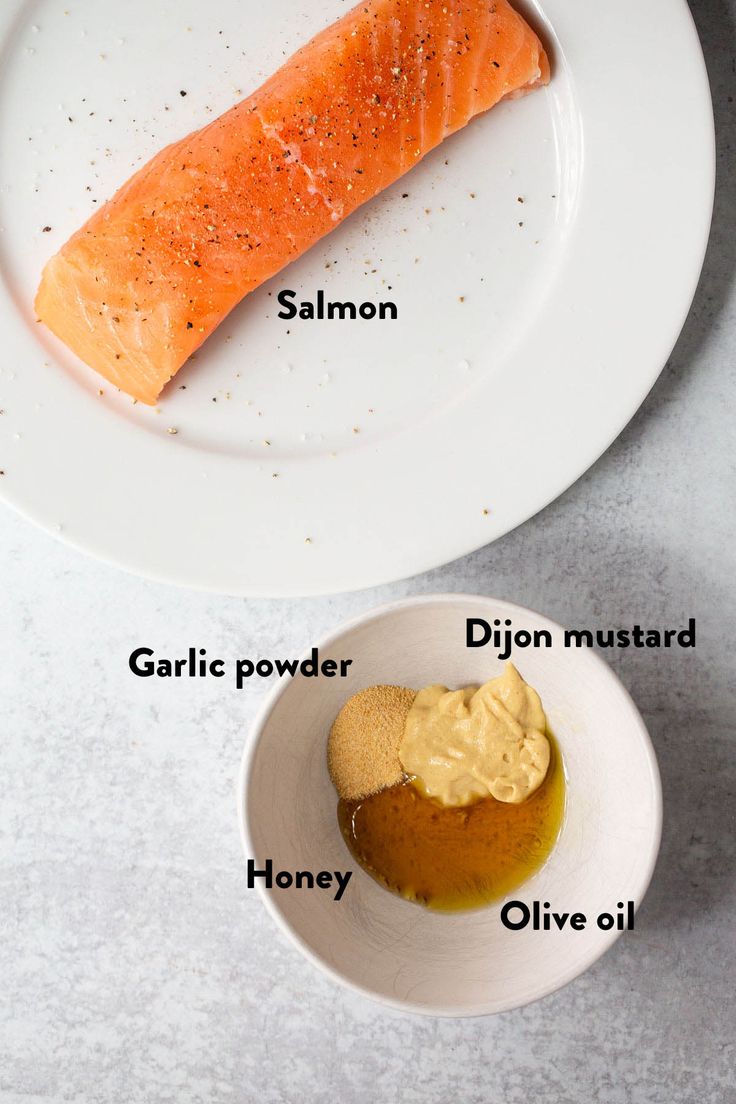 two plates with different types of food on them, one is salmon and the other has mustard