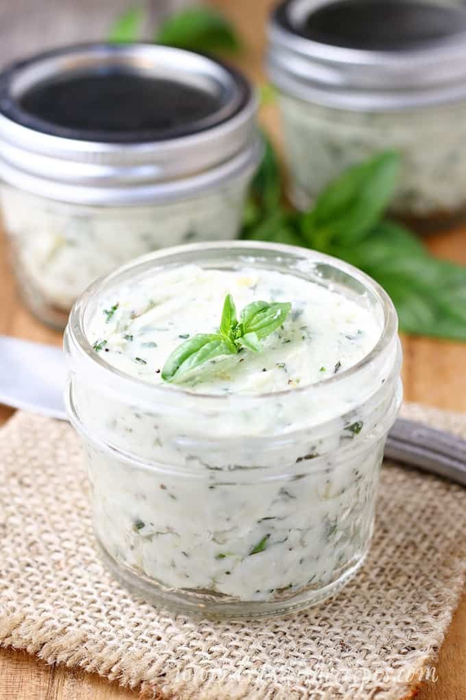 two jars filled with food sitting on top of a wooden table next to a knife