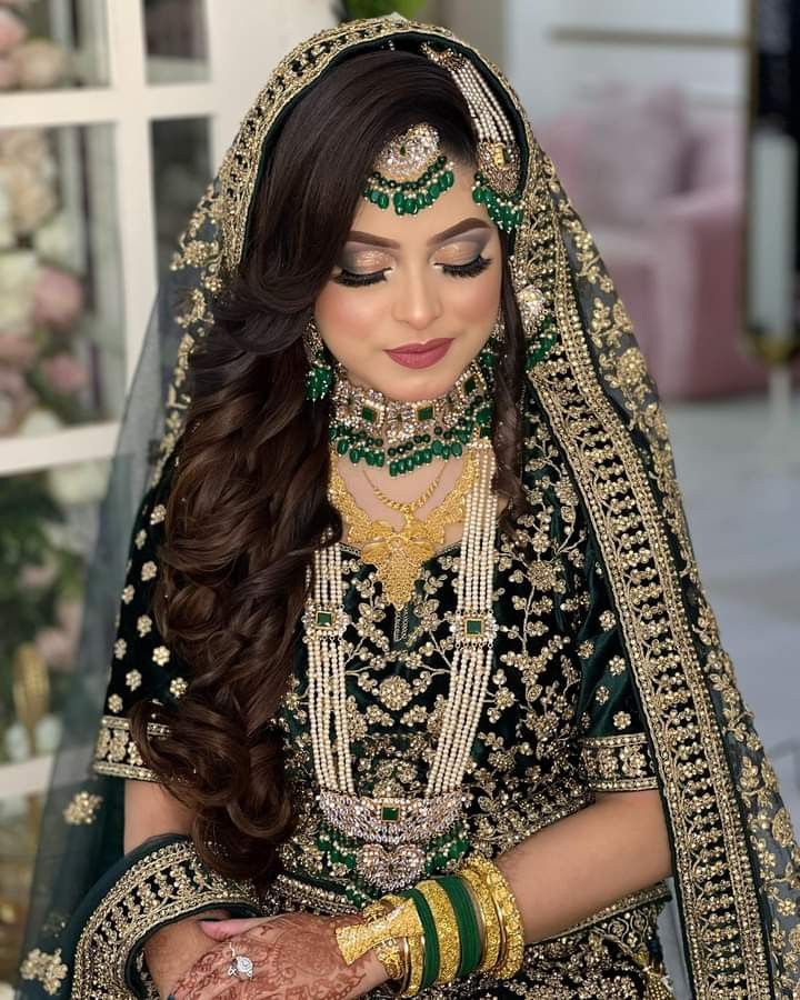 a woman in a black and gold bridal outfit with her hands on her chest