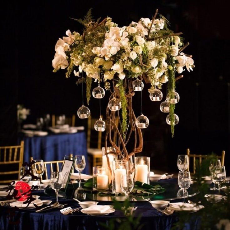 a centerpiece with candles and flowers on a table in a dark room at a wedding