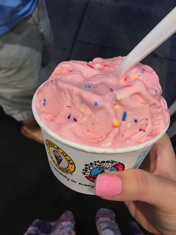 a person holding up a cup of ice cream with sprinkles on it