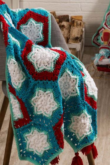 a crocheted blanket sitting on top of a chair next to a fire place