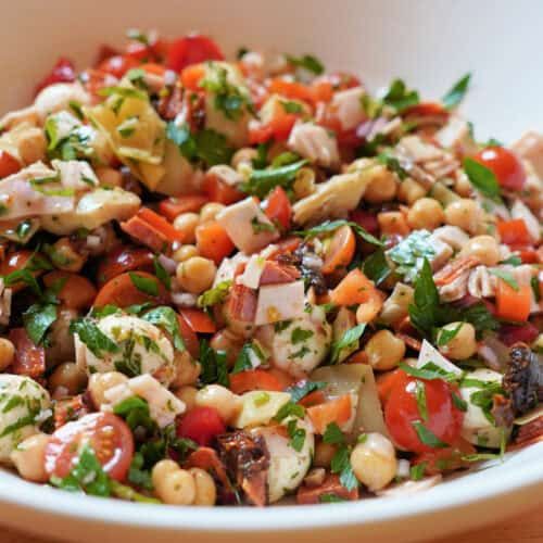 a white bowl filled with lots of different types of food on top of a wooden table