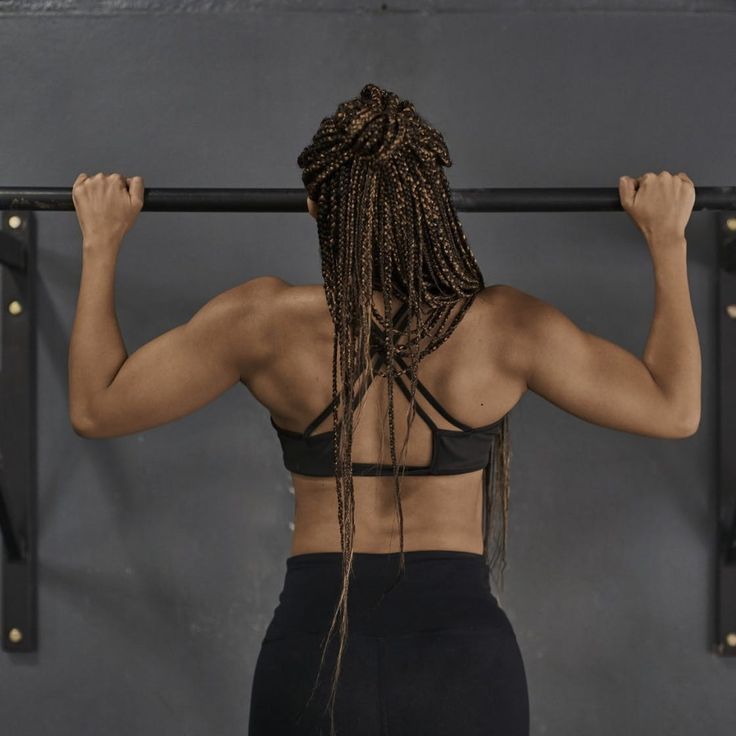 a woman is doing pull ups with her hands on the bar and looking at the wall