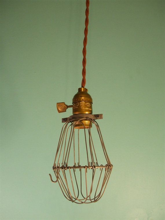 an old fashioned light fixture hanging from a wire on a green wall in a room