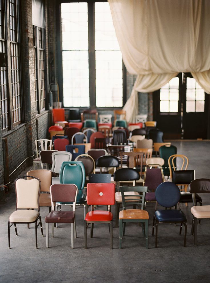 rows of chairs in an empty room with drapes hanging from the ceiling and windows