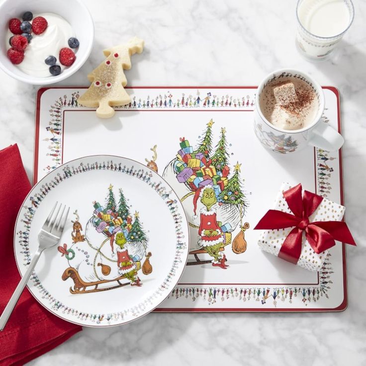 a place setting with christmas themed plates and utensils