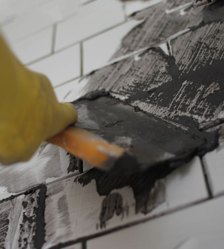 a person using a brush to paint the tile