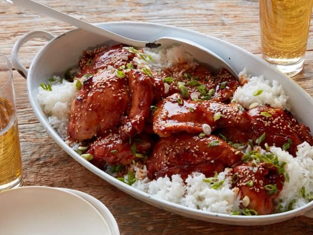 a bowl filled with meat and rice next to two glasses of beer on a table