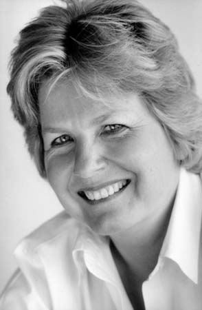 a black and white photo of a woman with blonde hair smiling at the camera,