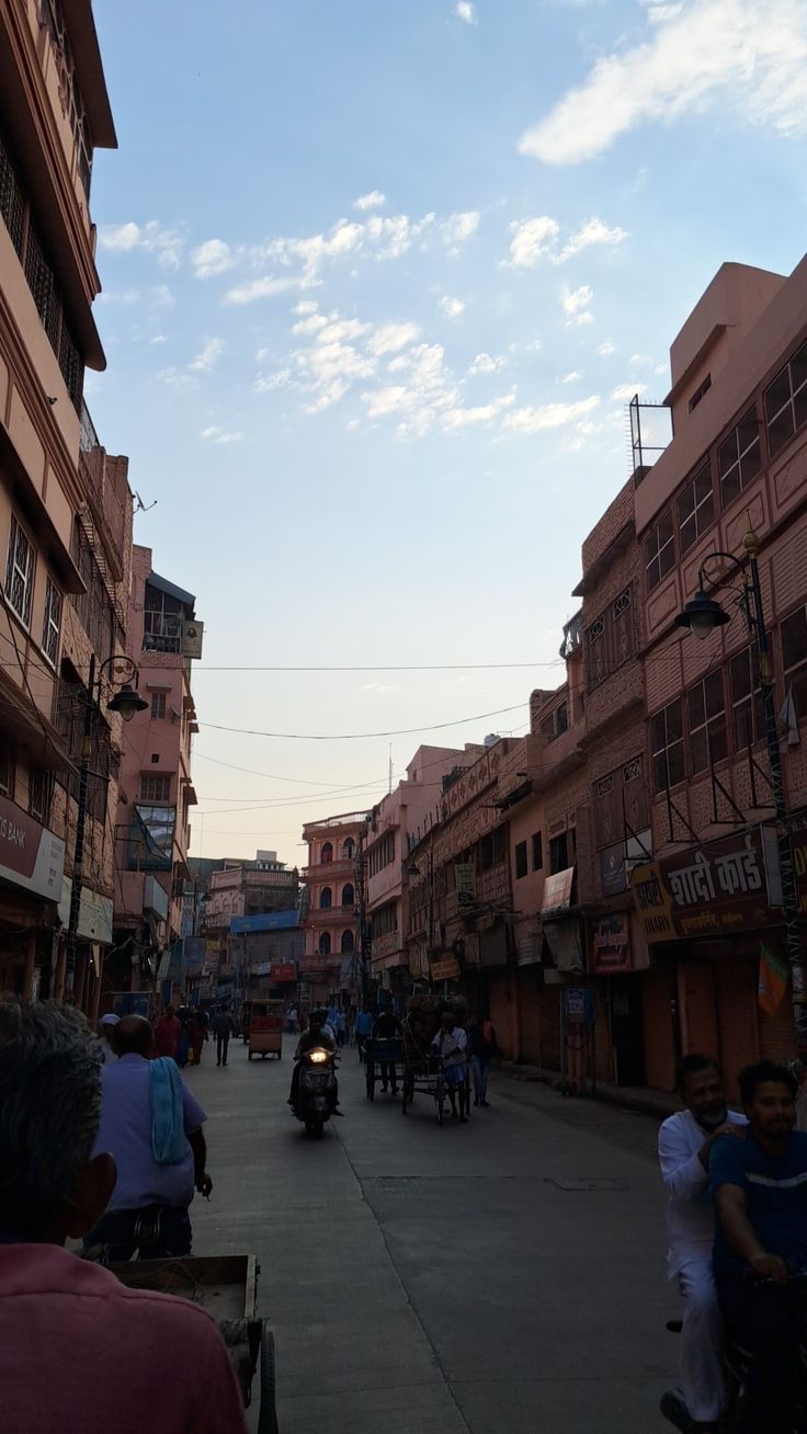 people are riding motorcycles down the street in an urban area with buildings on either side