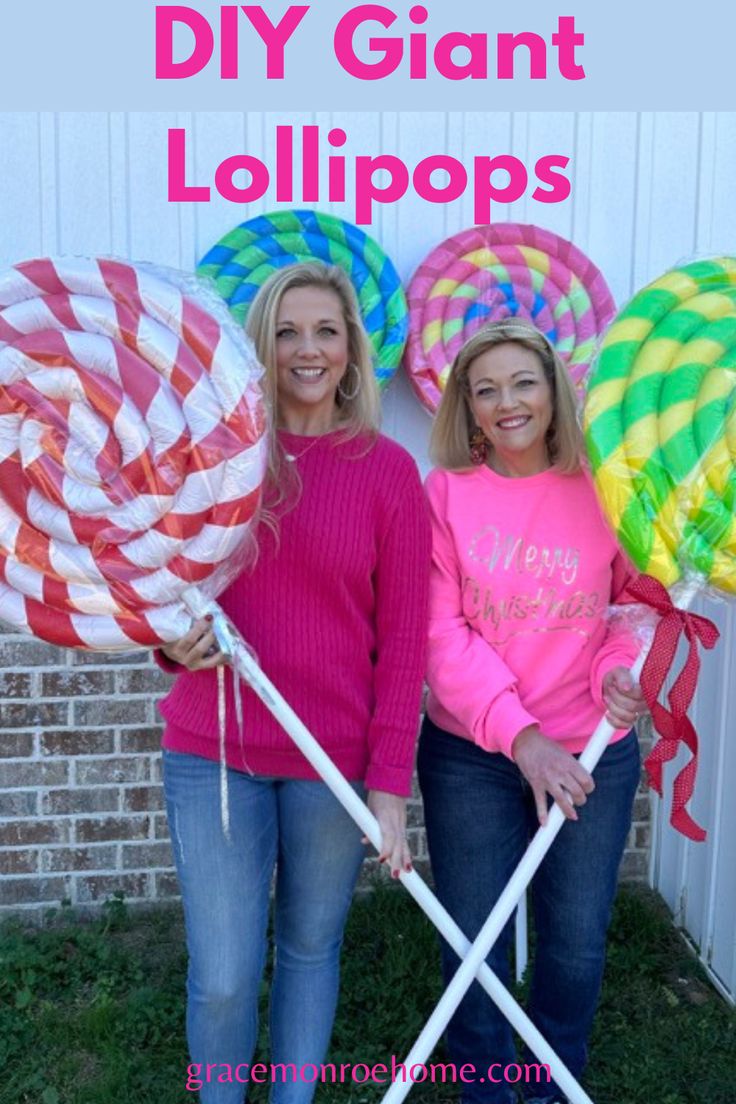 two women standing next to each other holding giant lollipops