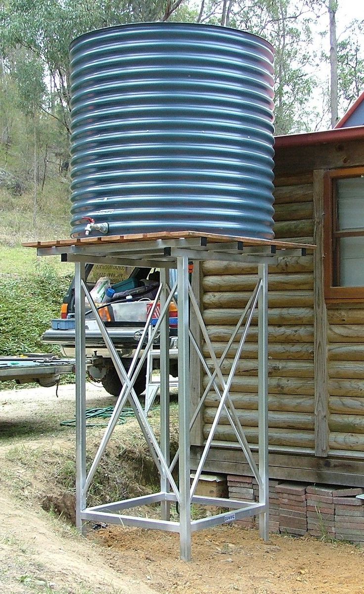 a small wooden cabin with a metal tank on the porch