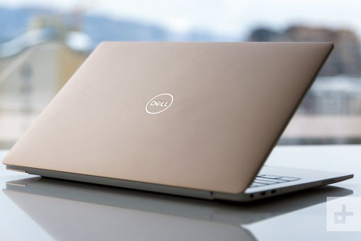 an open laptop computer sitting on top of a white table next to a large window