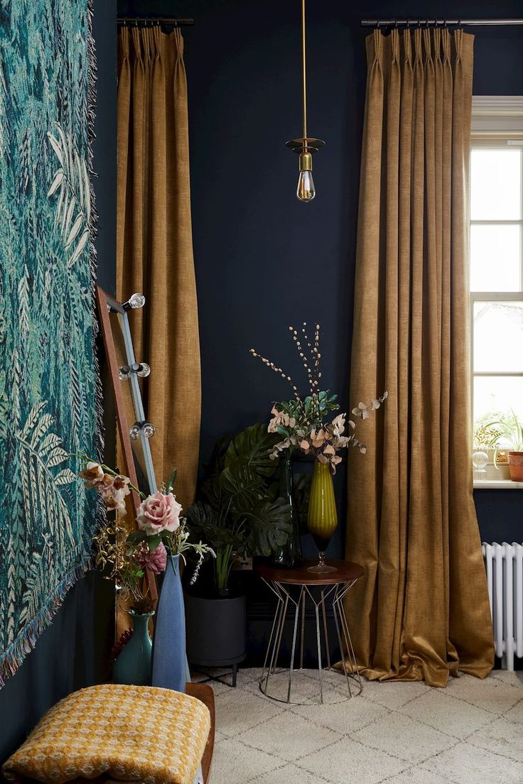 a living room with blue walls and curtains on the windowsills, a bench in front of a window