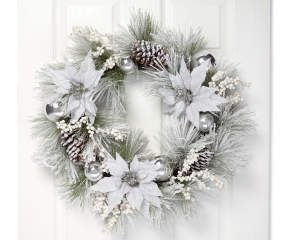 a christmas wreath hanging on the front door with silver ornaments and greenery around it