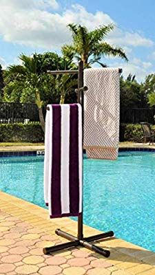 two towels hanging on a towel rack next to a swimming pool with palm trees in the background