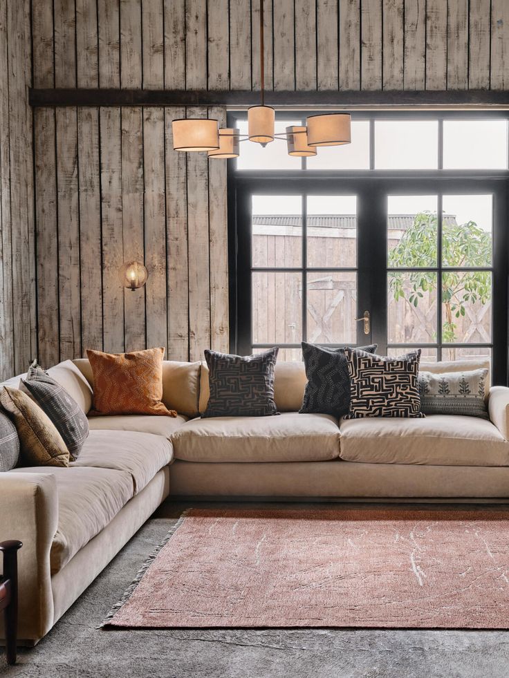 a living room filled with lots of furniture next to a large window and wooden walls