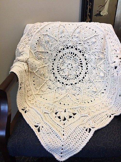 a white crocheted blanket sitting on top of a chair