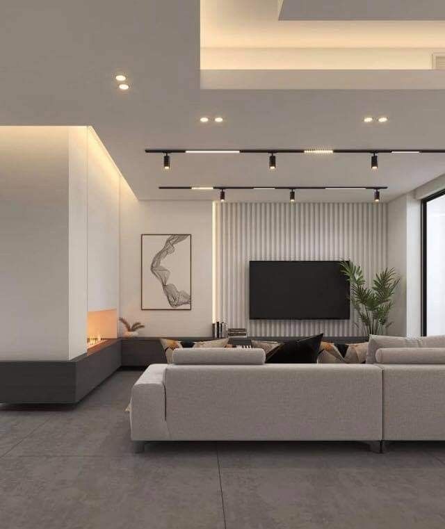 a modern living room with white walls and grey flooring, large sectional couches