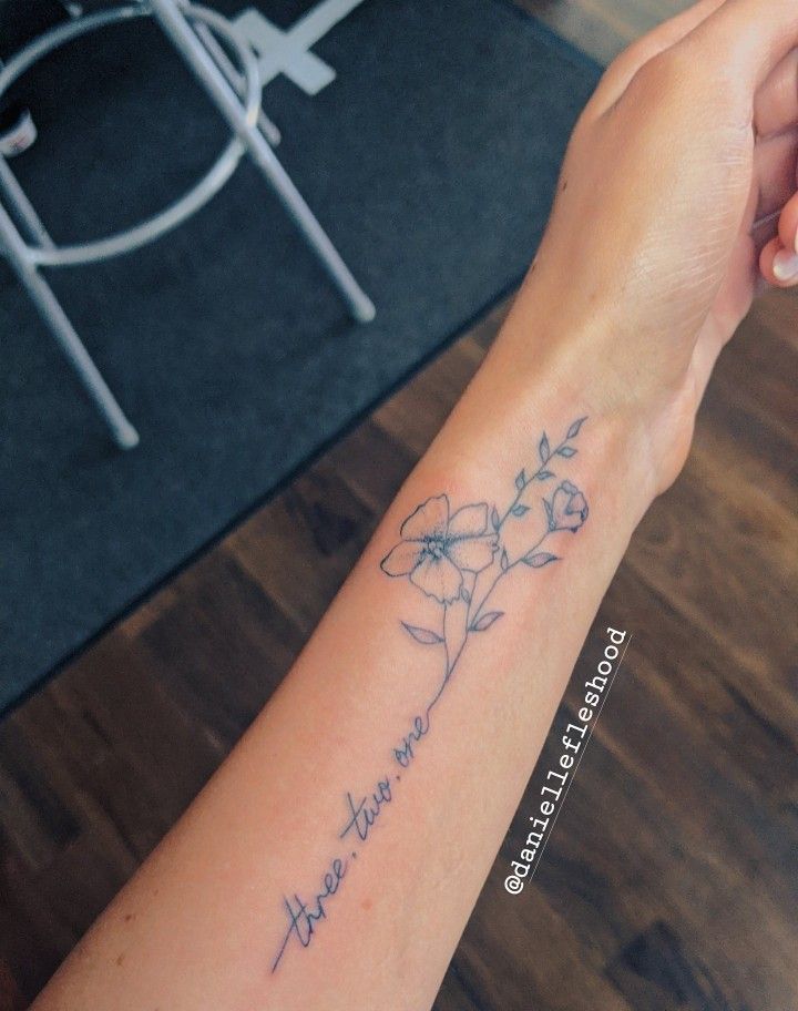 a woman's arm with a flower tattoo on it