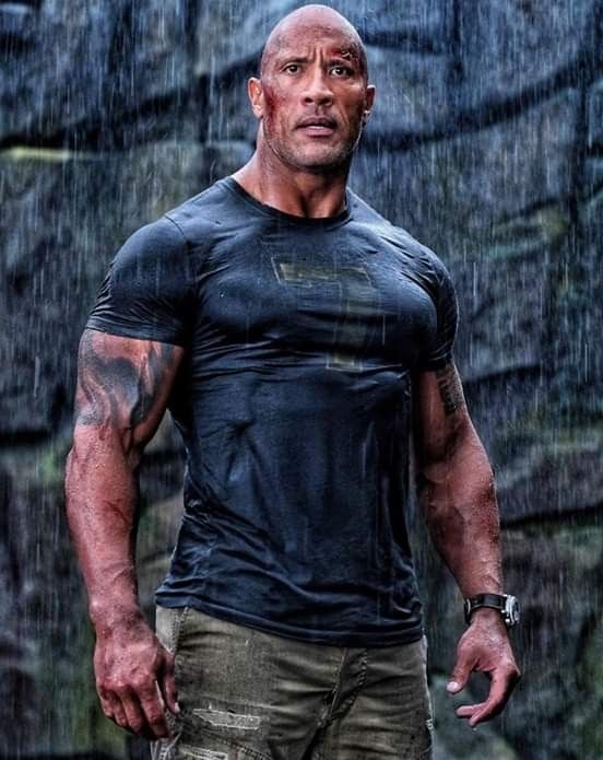 the rock standing in the rain with his hands on his hips