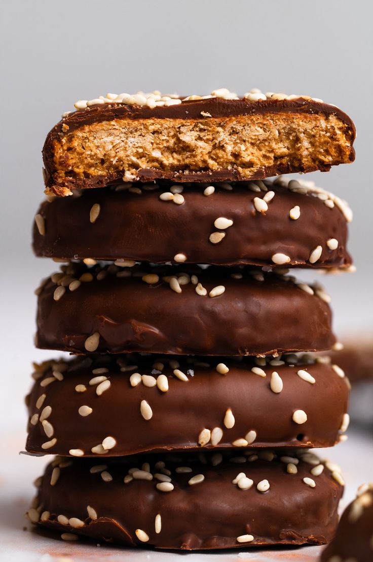 chocolate covered cookies stacked on top of each other with sesame seeds all over them and one cookie in the middle