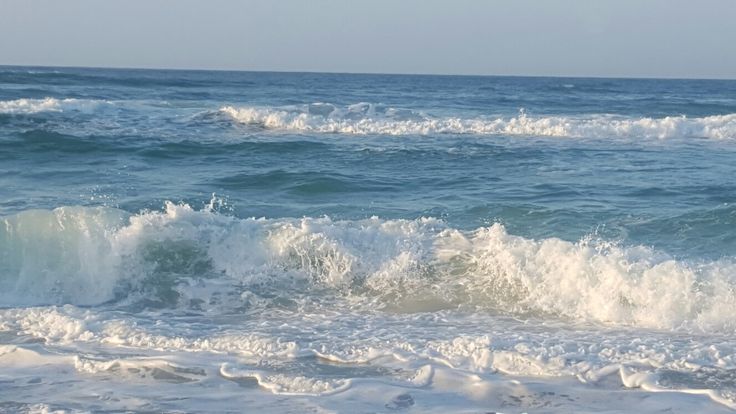 a man riding a surfboard on top of a wave in the ocean next to shore