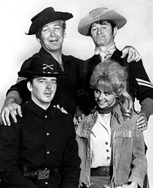 three men and two women in cowboy hats posing for a photo together, one man is holding his arm around the woman's shoulder