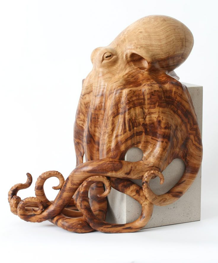 an octopus sculpture sitting on top of a block of concrete with its head turned to the side