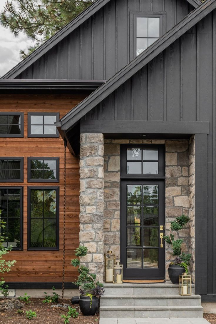 the front entrance to a house with black doors and stone steps leading up to it