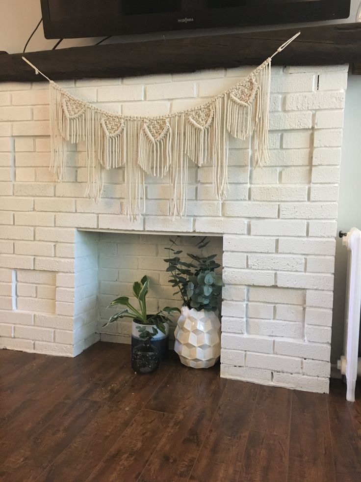 a white brick fireplace in a living room with potted plants on the mantel