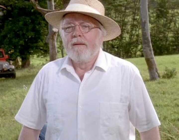 an old man wearing a hat and glasses standing in front of a red truck on the grass