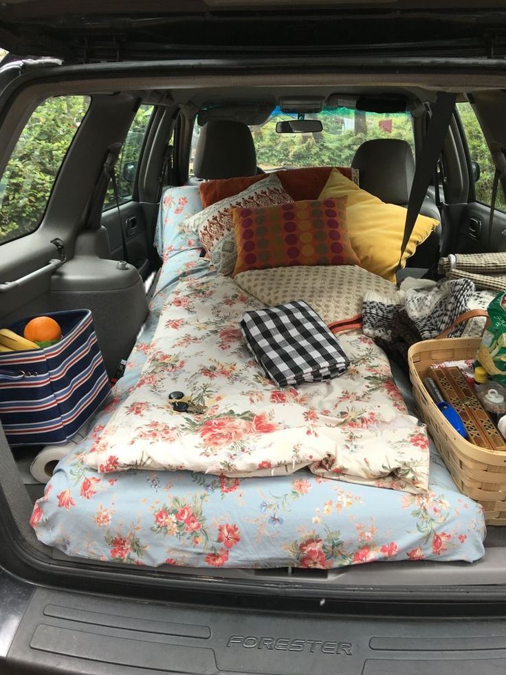 the back end of a car with an open trunk filled with blankets, pillows and other items