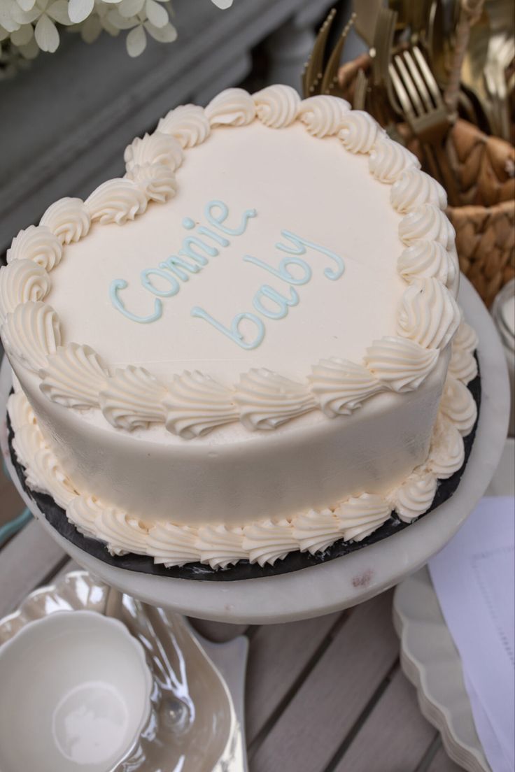 a white cake sitting on top of a table next to plates and silver utensils