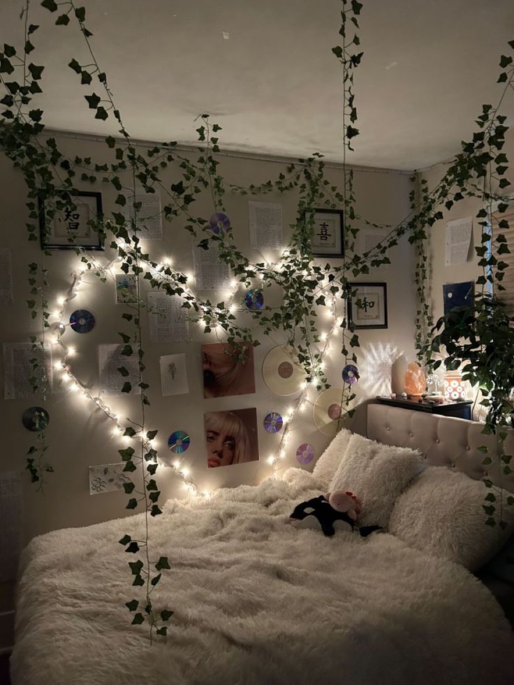 a bedroom decorated with plants and pictures on the wall, lights strung from the ceiling