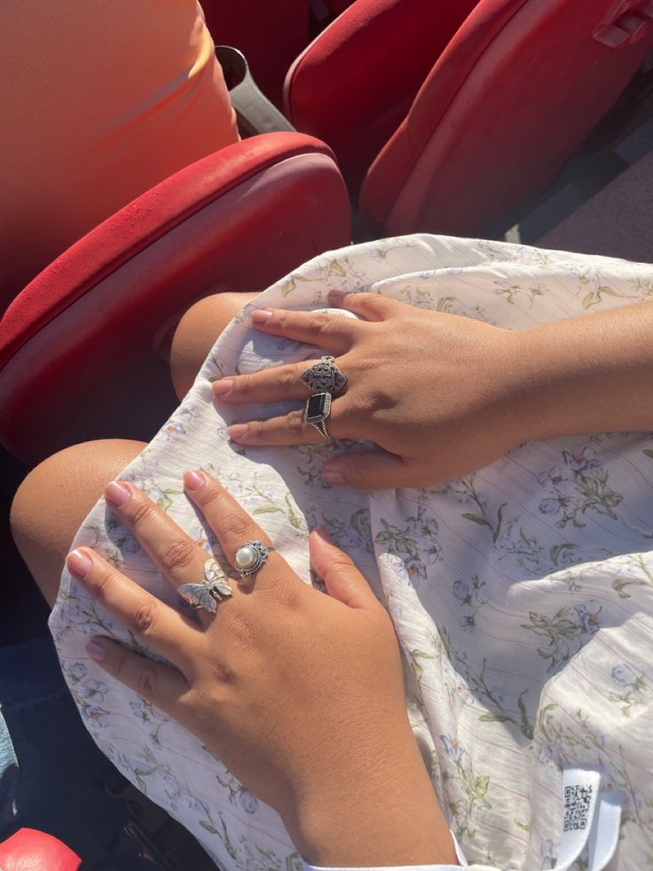 two women with wedding rings on their hands sitting in the stands at a baseball game