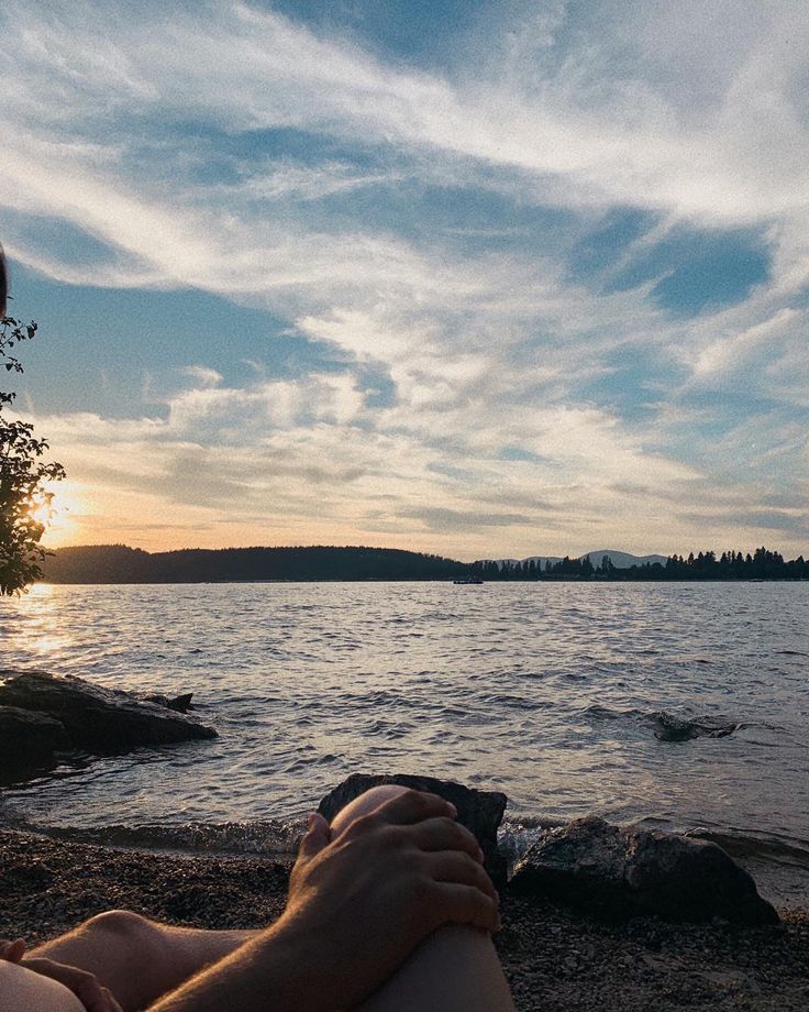 a person sitting on the beach watching the sun set