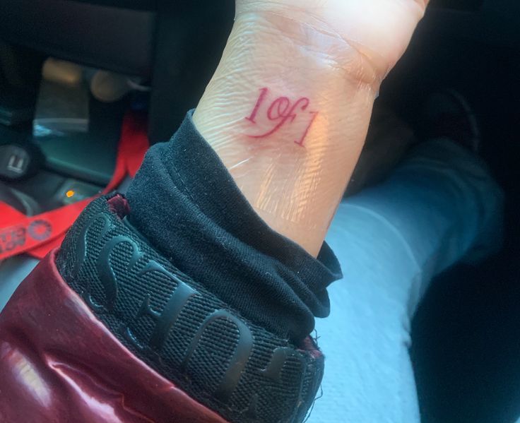 a woman's wrist tattoo with the word love written in red ink on it