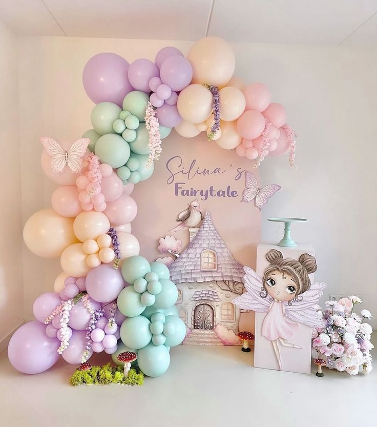 a balloon arch is decorated with pastel balloons and fairy decorations for a birthday party