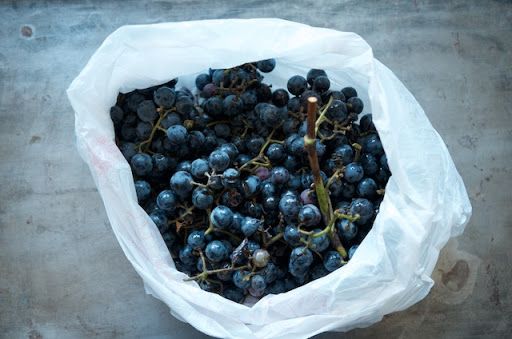 a bag full of grapes sitting on top of a table